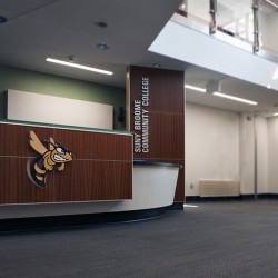 Interior image of lobby main desk featuring school hornet logo.