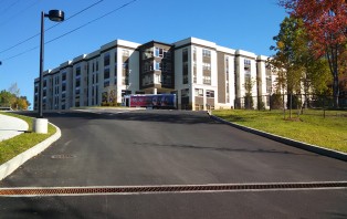 Image of lot access with drainage feature and building in the background.