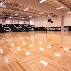 Interior image of school gymasium featuring wood floor.
