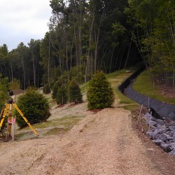 Image of land surveying equipment surrounded by landscaped features.