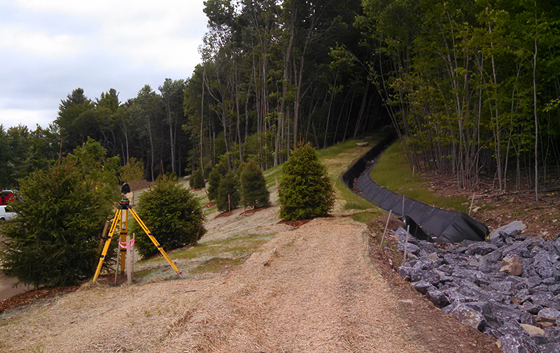 Image of land surveying equipment surrounded by landscaped features.