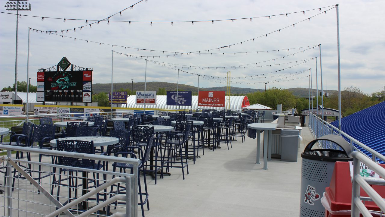 Picnic area at Mirabito Stadium, formerly NYSEG Stadium, featuring shaded tables, casual seating, and views of the field designed for fan gatherings and outdoor dining.