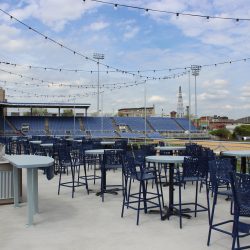 Picnic area at Mirabito Stadium, formerly NYSEG Stadium, featuring shaded tables, casual seating, and views of the field designed for fan gatherings and outdoor dining.